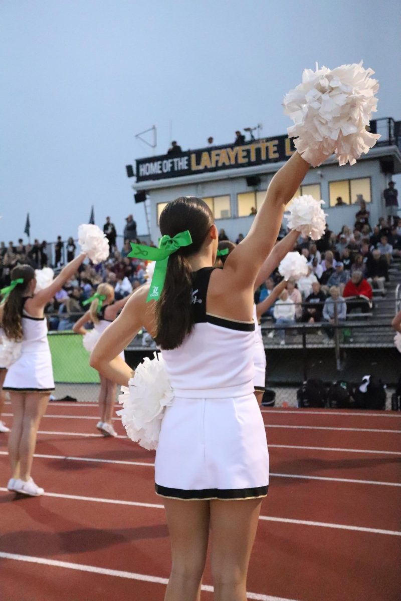 With green bows in their hair for mental health awareness night, Lafayette cheerleaders lead the crowd in a cheer.