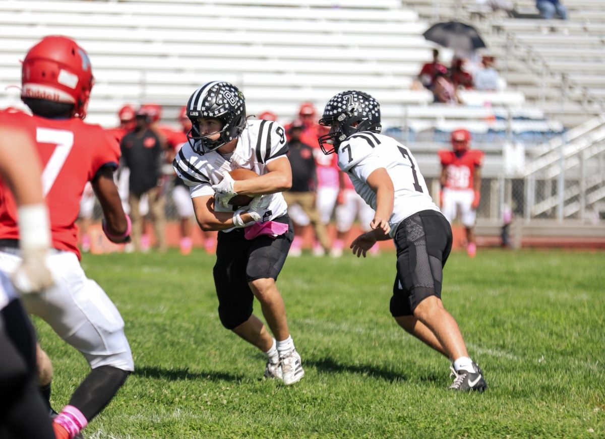 In an attempt to gain yardage, senior quarterback Brady Micek hands the ball off to junior running back Cody Keen. Lafayette defeated McCluer High School 63-6 on Saturday, Oct. 4.