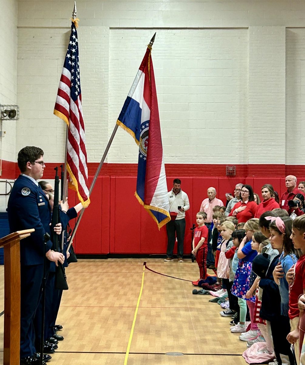 Senior Sam Niblett, flanked by his fellow color guard members, holds a position of attention for the Star Spangled Banner.