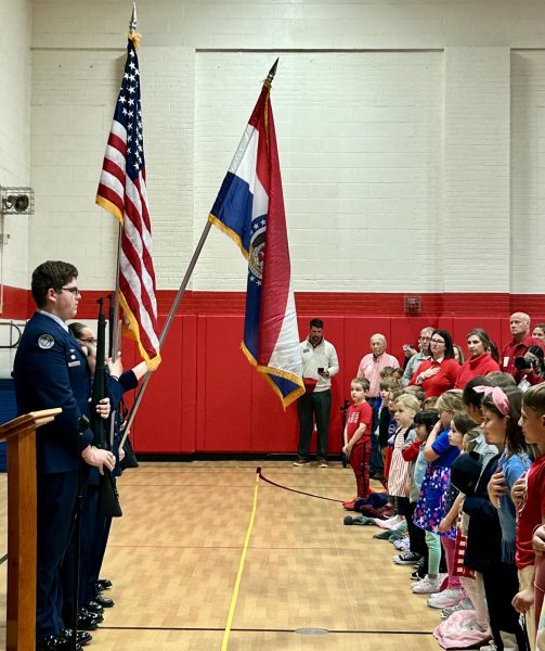 Senior Sam Niblett, flanked by his fellow color guard members, holds a position of attention for the Star Spangled Banner.