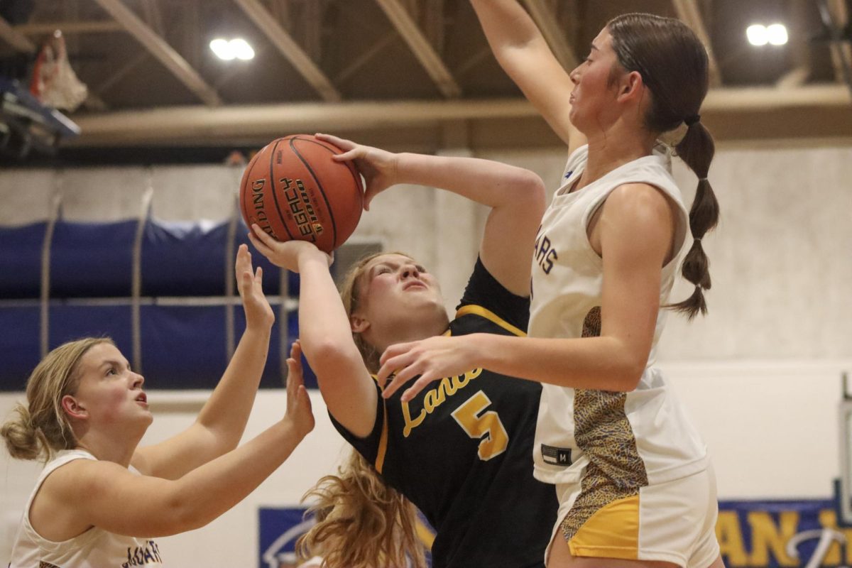 Sandwiched between two guards, senior forward Annika Kivisikk shoots a basket. Kivisikk went 3-for-5 from the field.