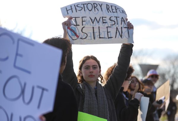 Among the student protestors, sophomore Zoe Faw raises her sign that reads "History repeats if we stay silent." "It felt powerful making a statement, even if others harshly disagreed with us," Faw said. "Going out as a community, as well, showed that there are others who care and aren't ashamed to stand up for what is right." 