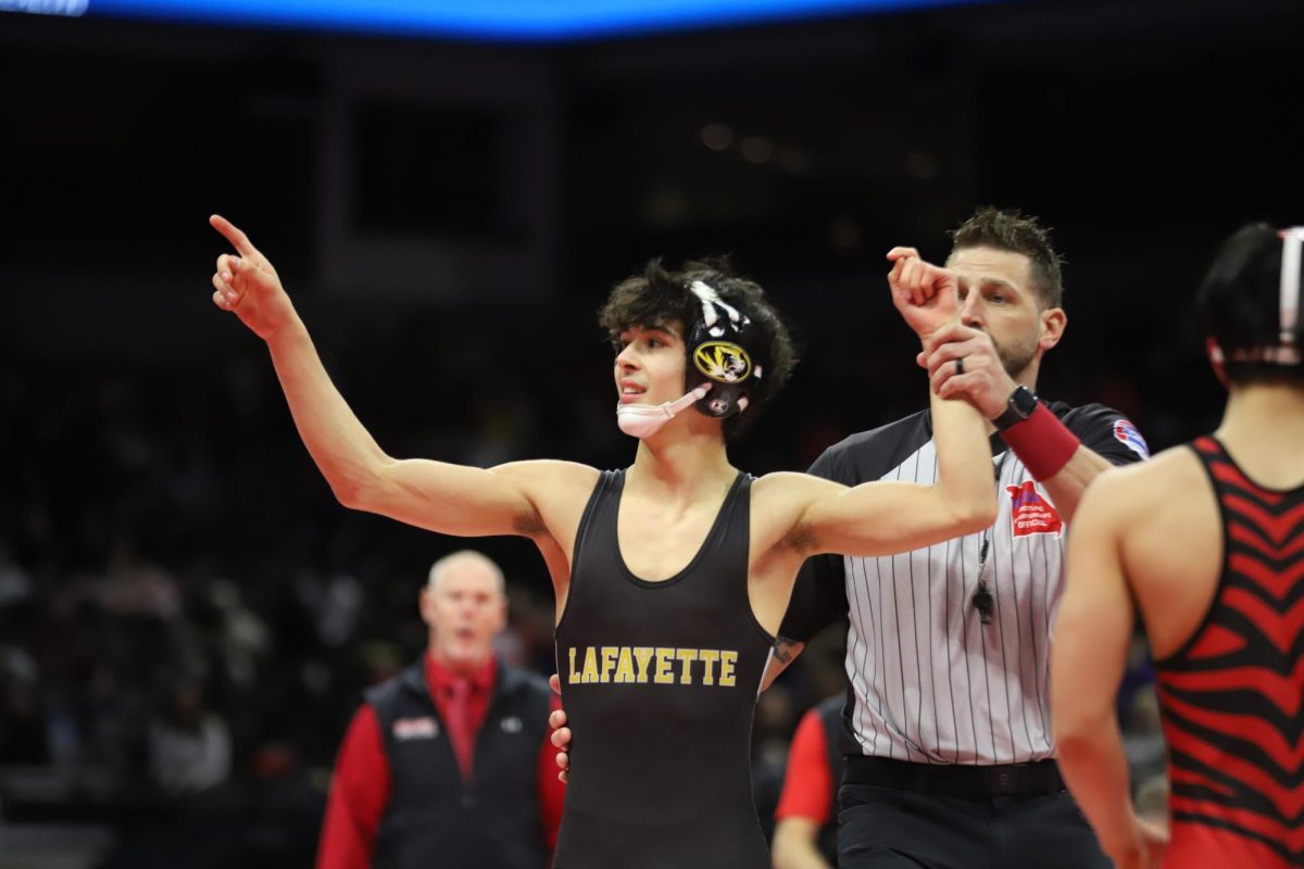 After his win in the consolation semifinal, junior Max Rowe (113) points to the crowd as the referee raises his arm to identify the winner. Rowe pinned his opponent, freshman Taiga Kwon of Ozark High School, in just 30 seconds. "My mindset was to wrestle as hard as I can and no holding back," Rowe said. 