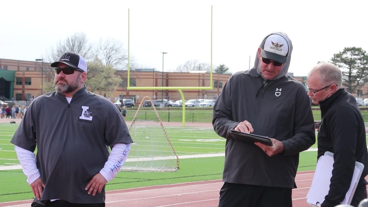 Boys Head Track Coach Scott Haxton discusses team details with fellow coaches.