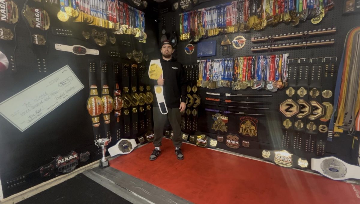 Holding a championship belt from the Double Gold Invitational, senior Mason Stritzel stands in the center of the trophy room at his house. This room contains a total 372 pieces of hardware from tournaments all over the United States.